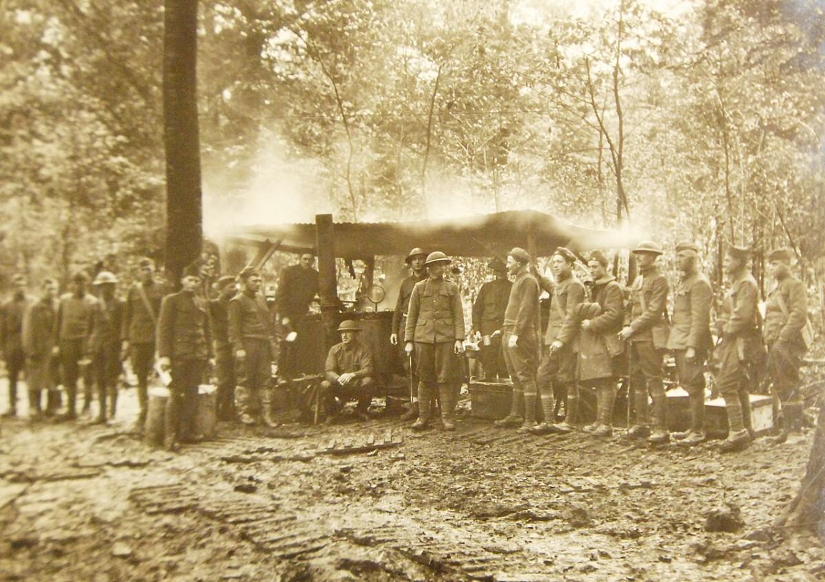 Soldiers gathered around a steaming field kitchen in a French forest